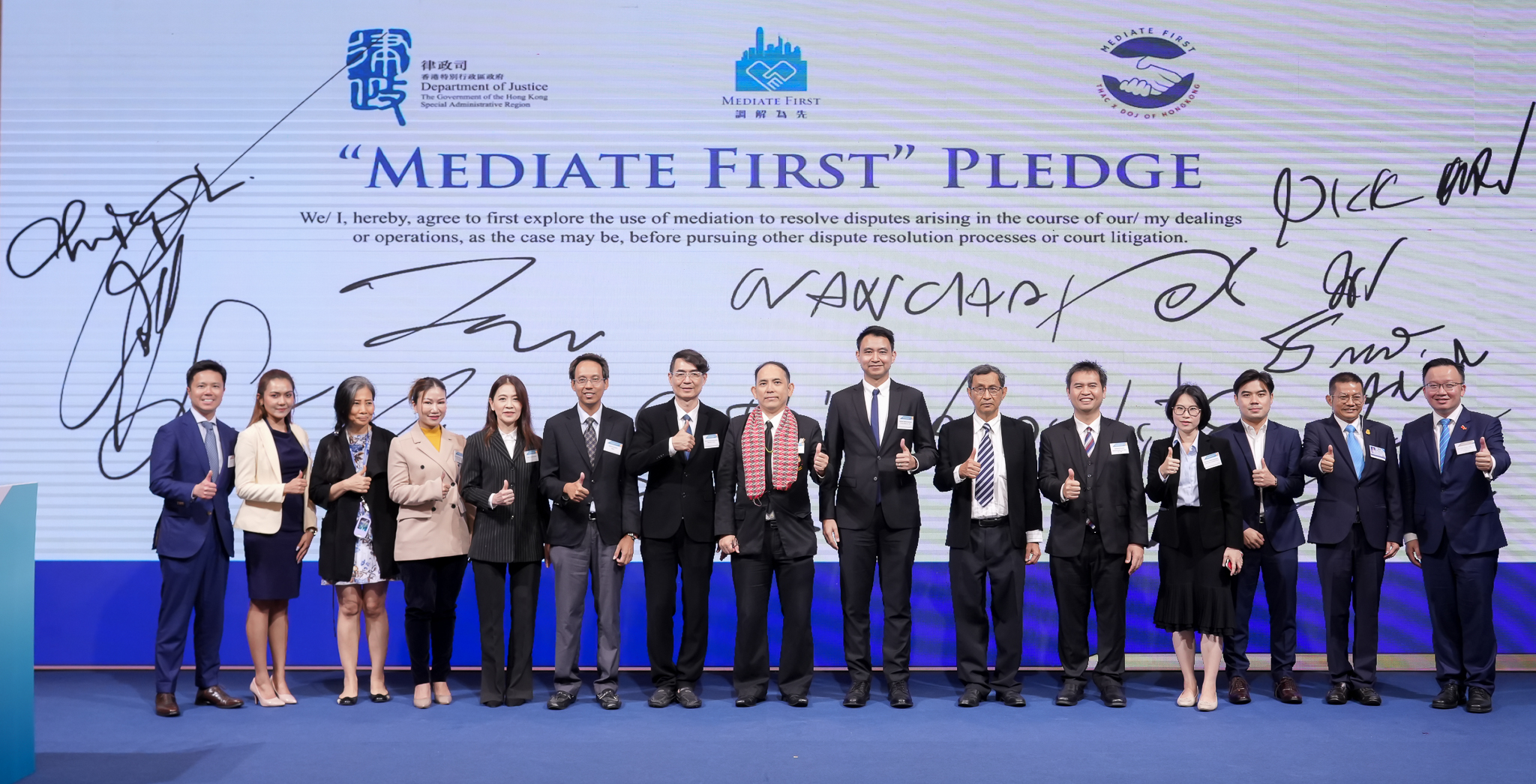 Signatories of the Mediate First Pledge standing in front of the signed pledge board at the Resolve2Win campaign in Bangkok